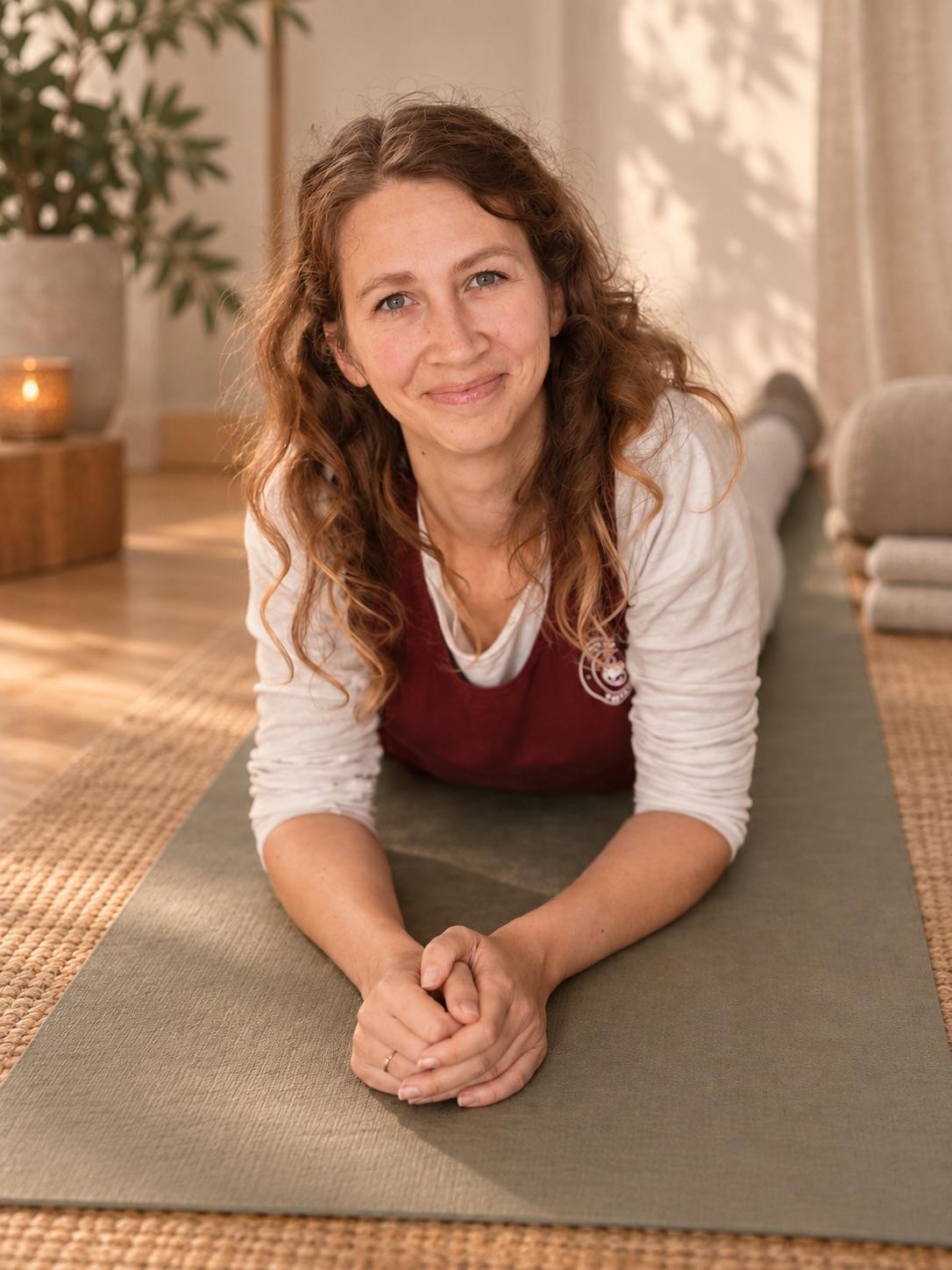 Mandy liegt auf der Yogamatte, stützt sich auf die Unterarme und lächelt in die Kamera